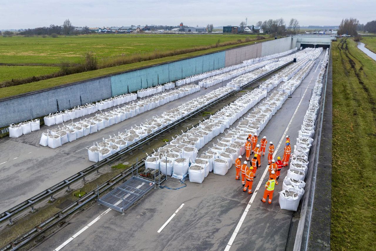 Medewerkers staan tussen de zandzakken bij de Prinses Margriettunnel op de snelweg A7 tussen Joure en Sneek.