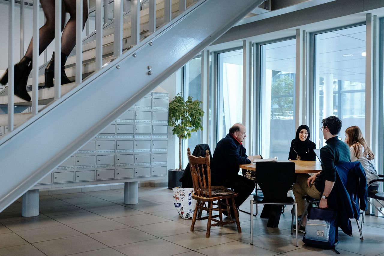 Gert Regterschot (links) met studenten onder de trap van een studentenflat in Eindhoven, waar hij dagelijks zit.