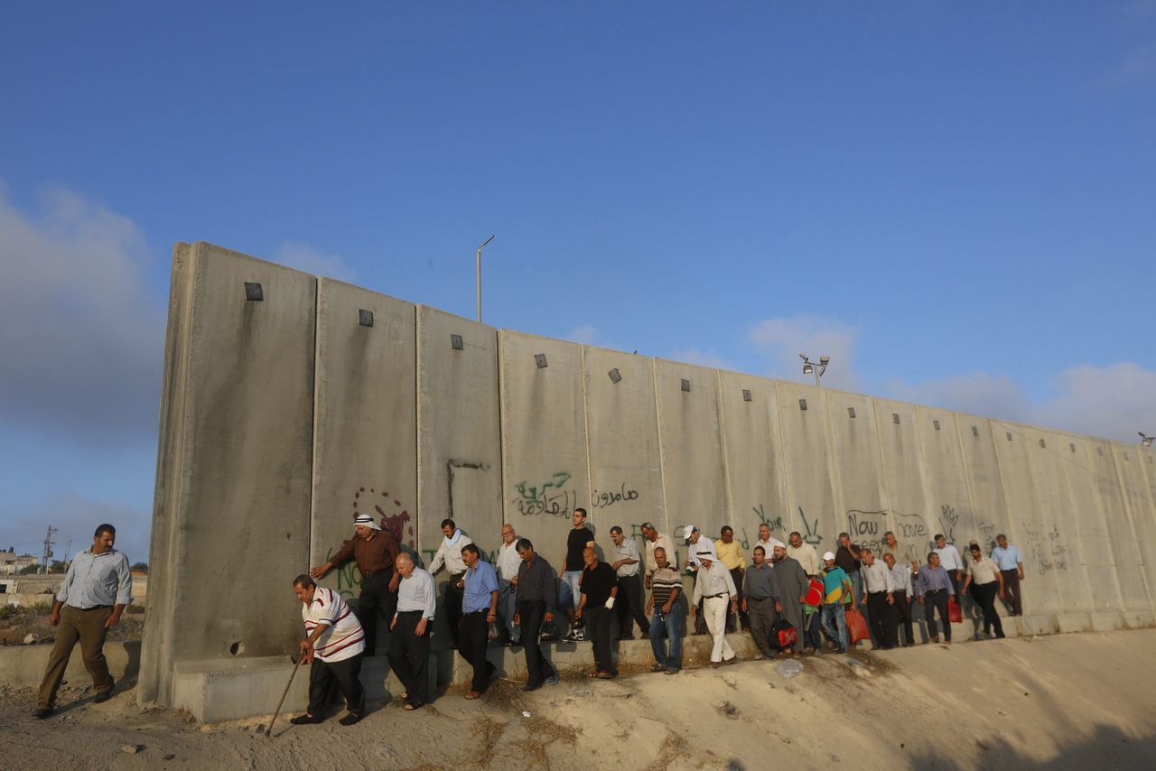 Palestijnse mannen lopen langs de muur van de Westoever bij Ramallah.