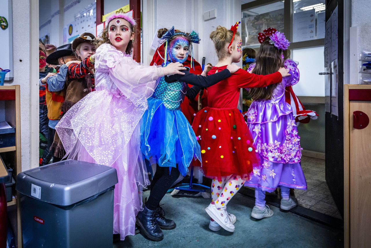 Tijdens het scholierencarnaval dansen kinderen van de Tarcisiusschool in Heerlen de polonaise door een klaslokaal.