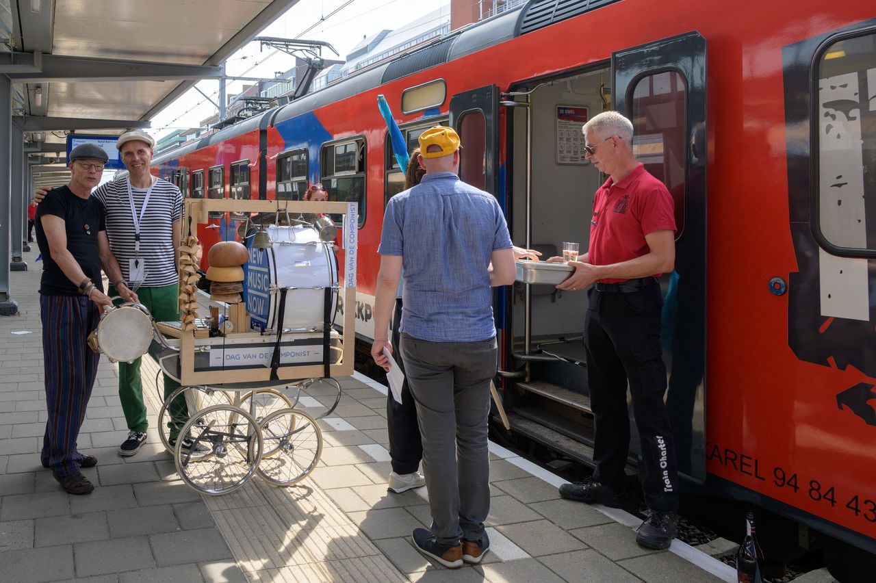 Martin Fondse heeft zijn arm om een bandlid geslagen op het perron van station ’s-Hertogenbosch op de Dag van de Componist voor het vertrek van de New Music Now Express.