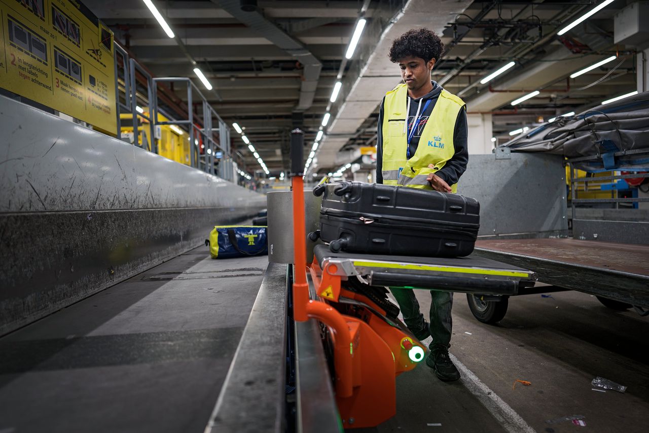 De transfer belt van het Deense Power Stow is een flexibel lopend bandje dat aan de grote bagageband hangt. Koffer uit de container, op het bandje, naar de grote band.