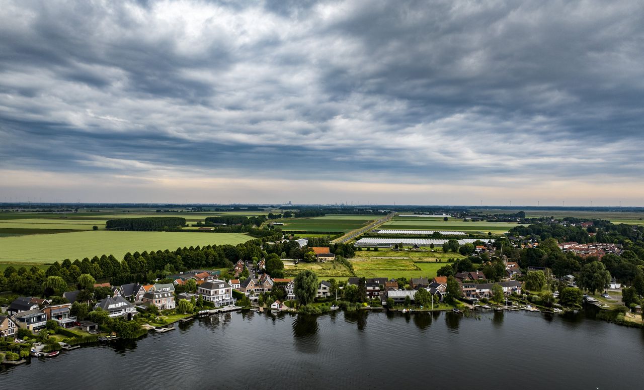 Een dronefoto van een dreigende regenbui boven een woonwijk in Nederland.