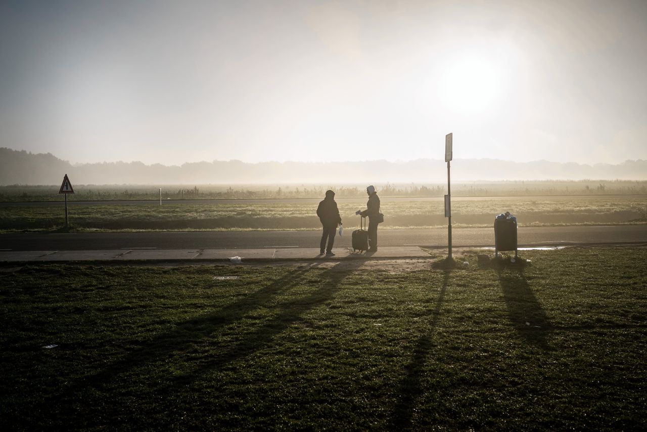 Asielzoekers in de vroege ochtend bij een bushalte in de buurt van het aanmeldcentrum in Ter Apel.