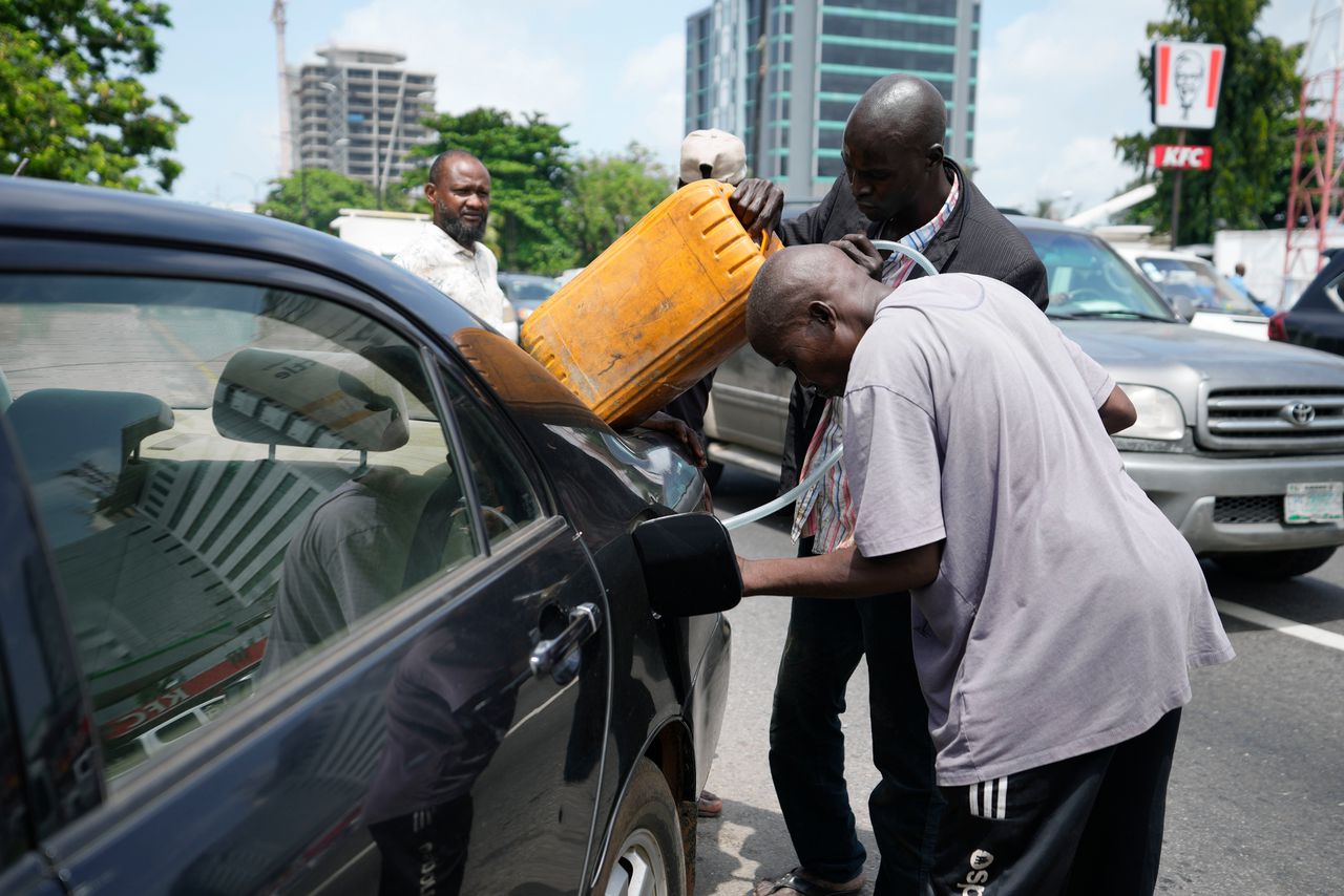 Een man koopt eind mei brandstof voor zijn auto op straat in Lagos, vlak nadat de officiële prijzen fors zijn gestegen door de afschaffing van de brandstofsubsidie.