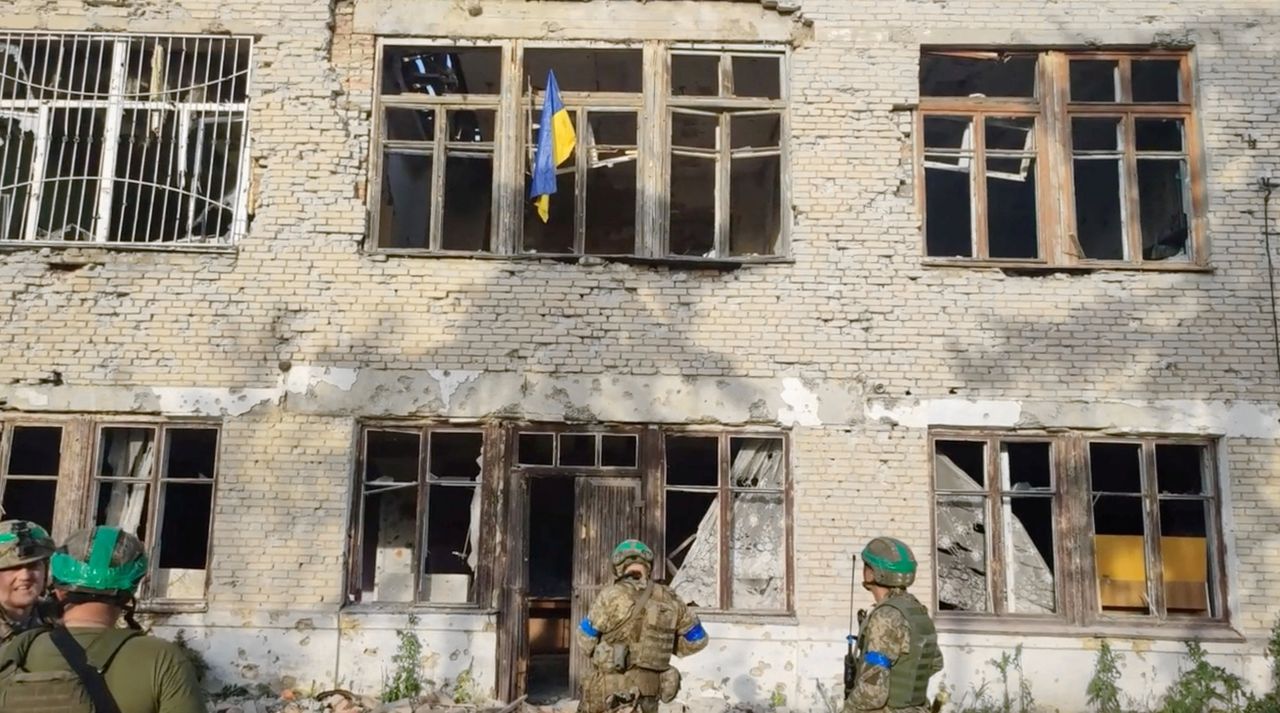 Oekraïense soldaten staan bij een gebouw met een Oekraïense vlag, na de vermoedelijke bevrijding van een dorp in de regio Donetsk dat wordt aangeduid als Blahodatne, op een beeld van een video die zondag is verspreid door de Oekraïense strijdkrachten.