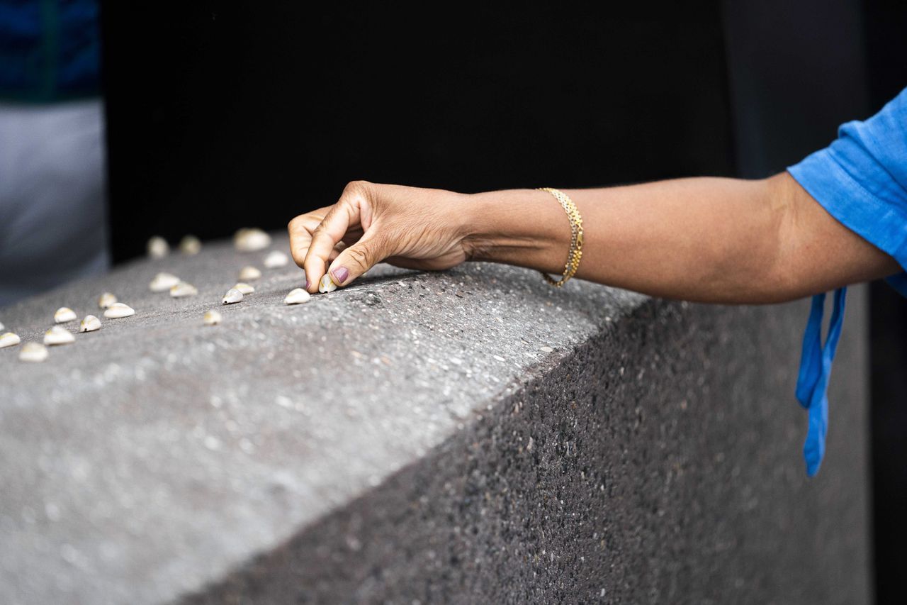 Bezoekers leggen schelpjes op een nieuw monument tijdens de herdenking van het slavernijverleden in Utrecht.