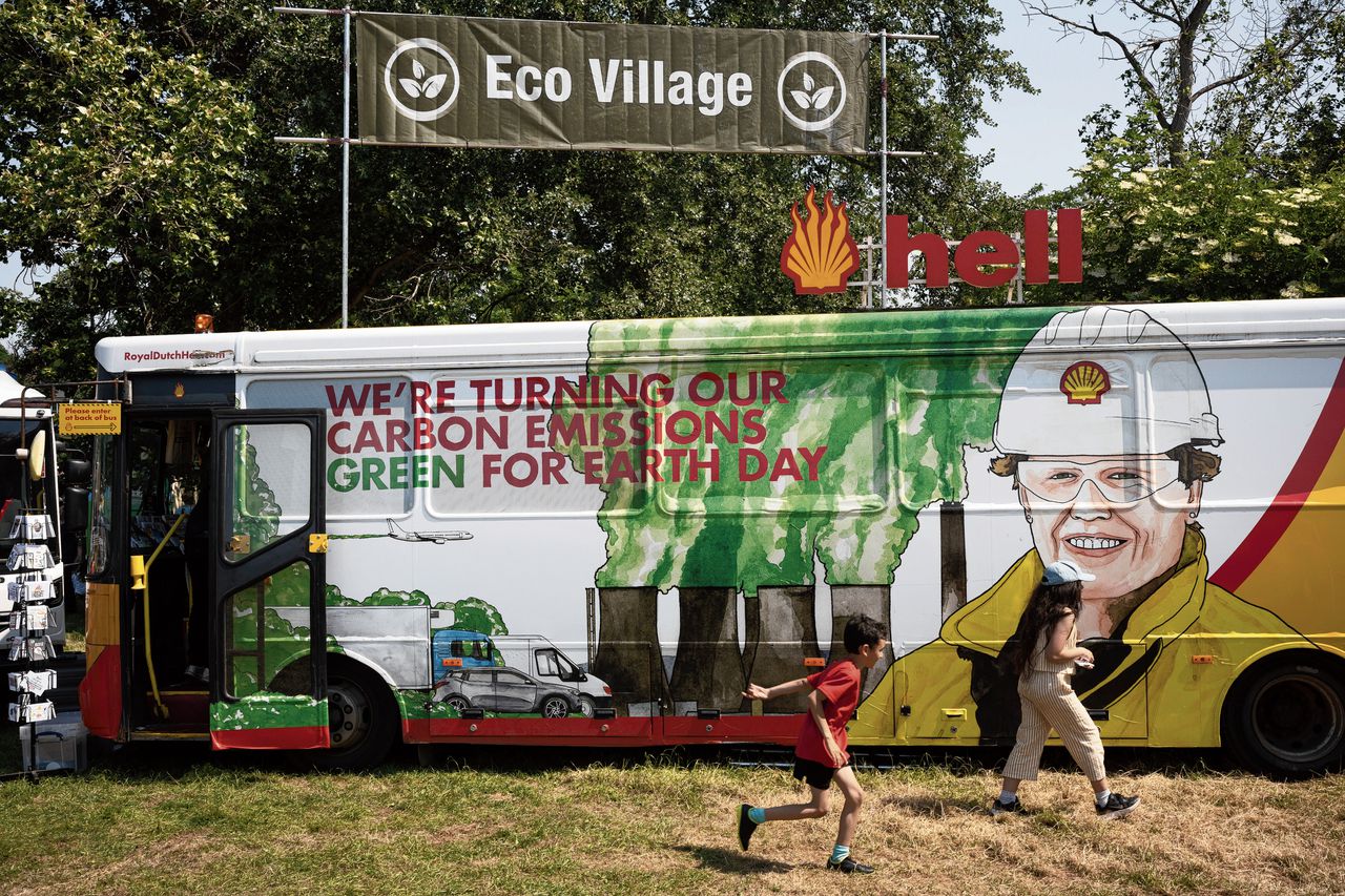 Kinderen rennen in Londen langs een protestbus die de uitstoot van Shell parodieert.