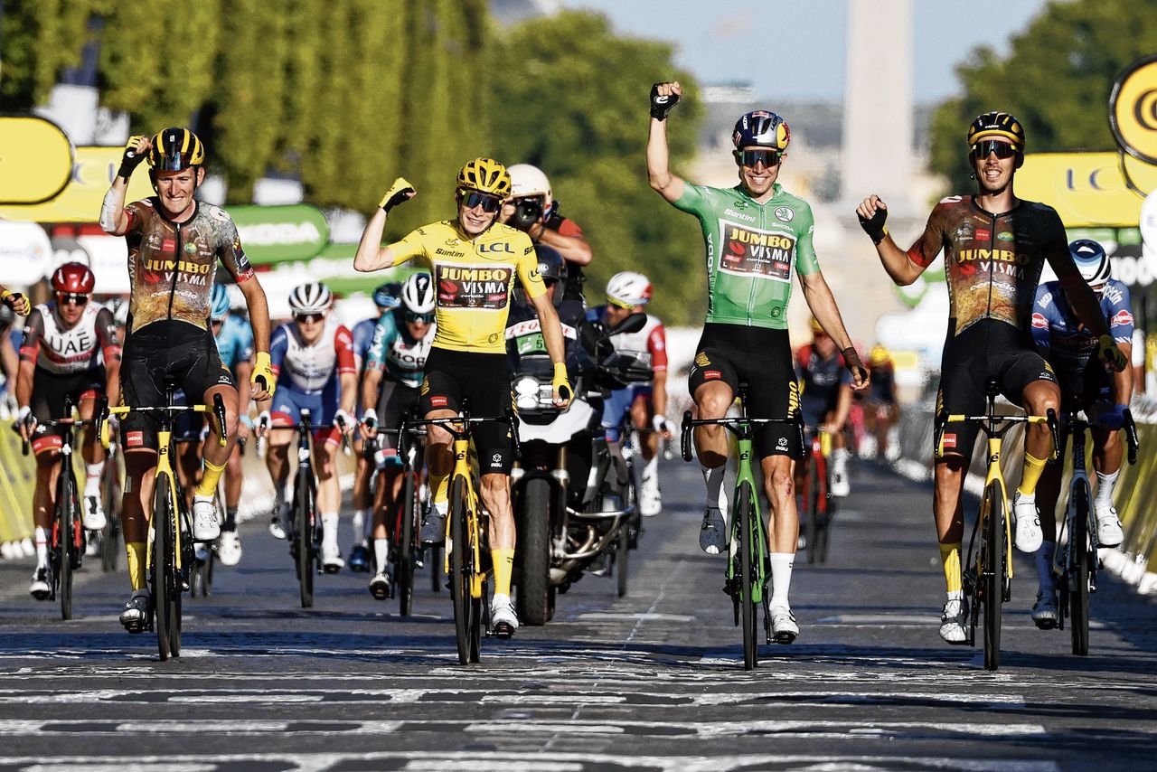 Jonas Vingegaard (geel) en Wout van Aert (groen) vieren het Tour-succes van 2022 met ploeggenoten van Jumbo-Visma in Parijs.