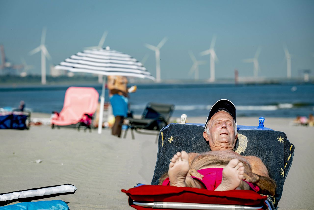 Een man geniet van de zon op het strand van Hoek van Holland.