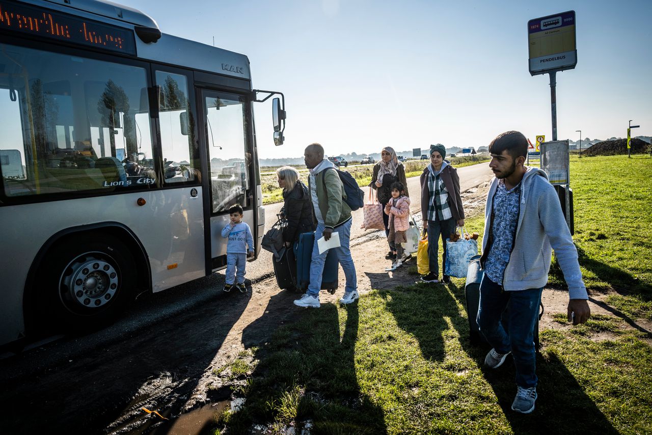 Asielzoekers wachten buiten Ter Apel op een bus.