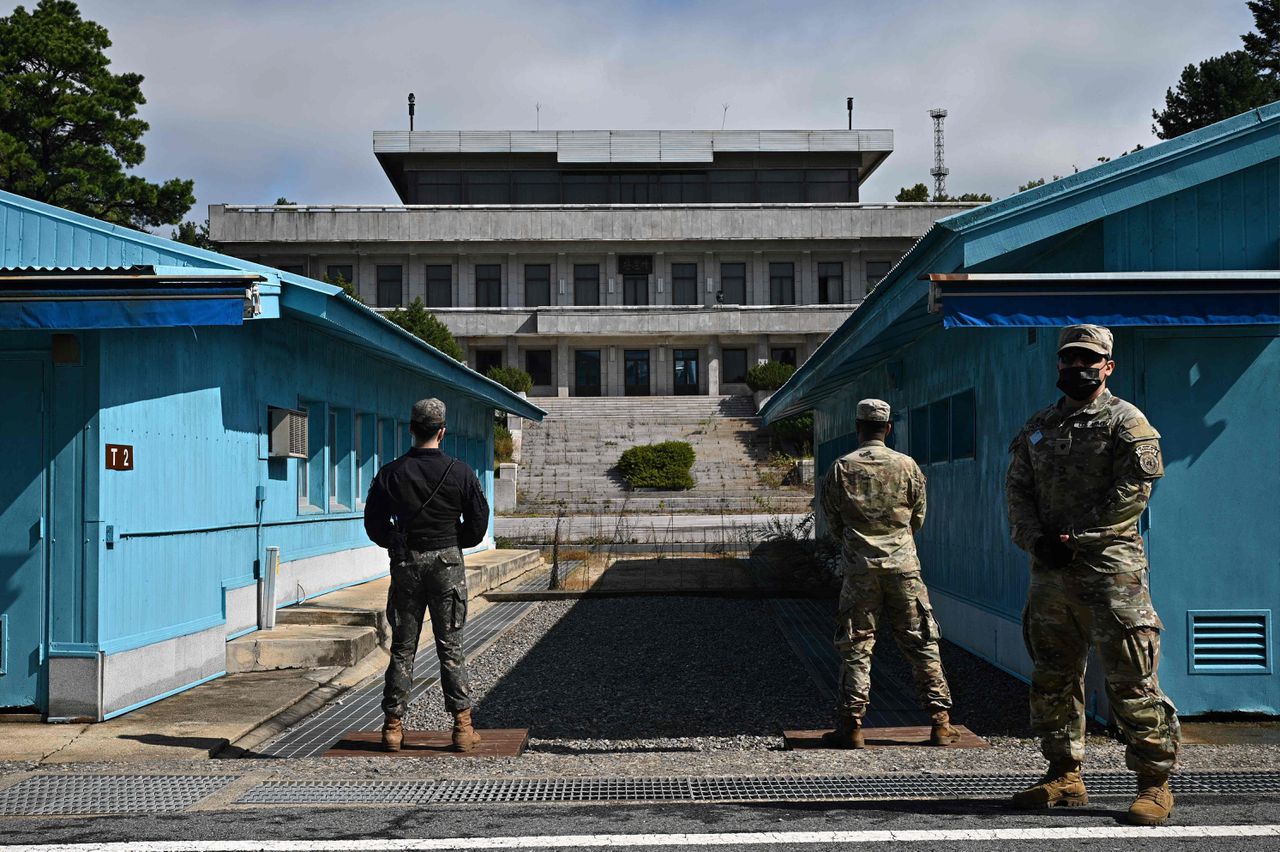 Een Zuid-Koreaanse soldaat (links) en VN-militairen (rechts) staan in oktober 2022 op wacht bij de blauwe huisjes in Panmunjom, aan de grens tussen Noord- en Zuid-Korea.