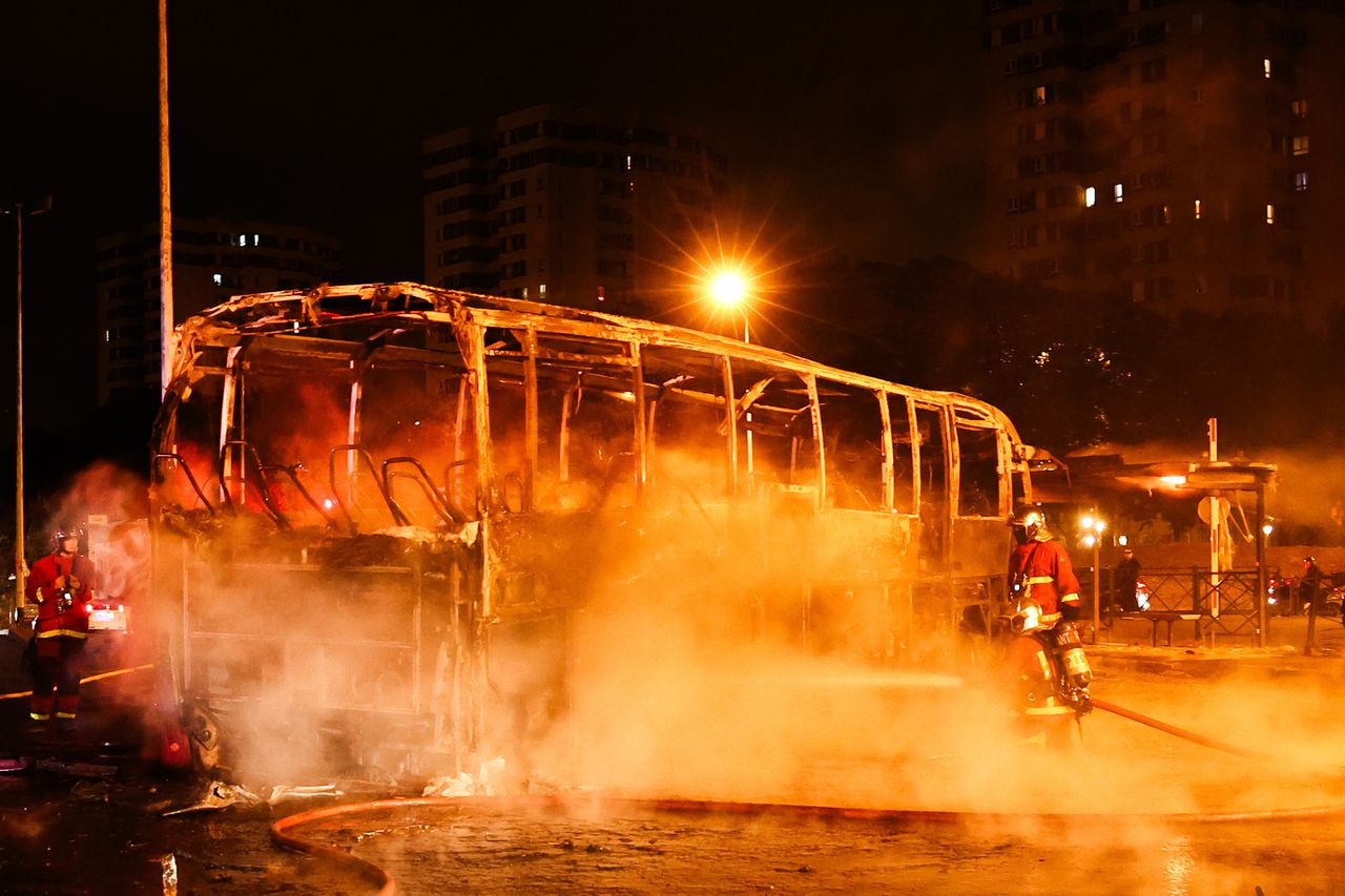 Brandweerlieden blussen vrijdag een bus die in brand is gestoken bij confrontaties tussen betogers en oproerpolitie in Nanterre, een voorstad van Parijs.