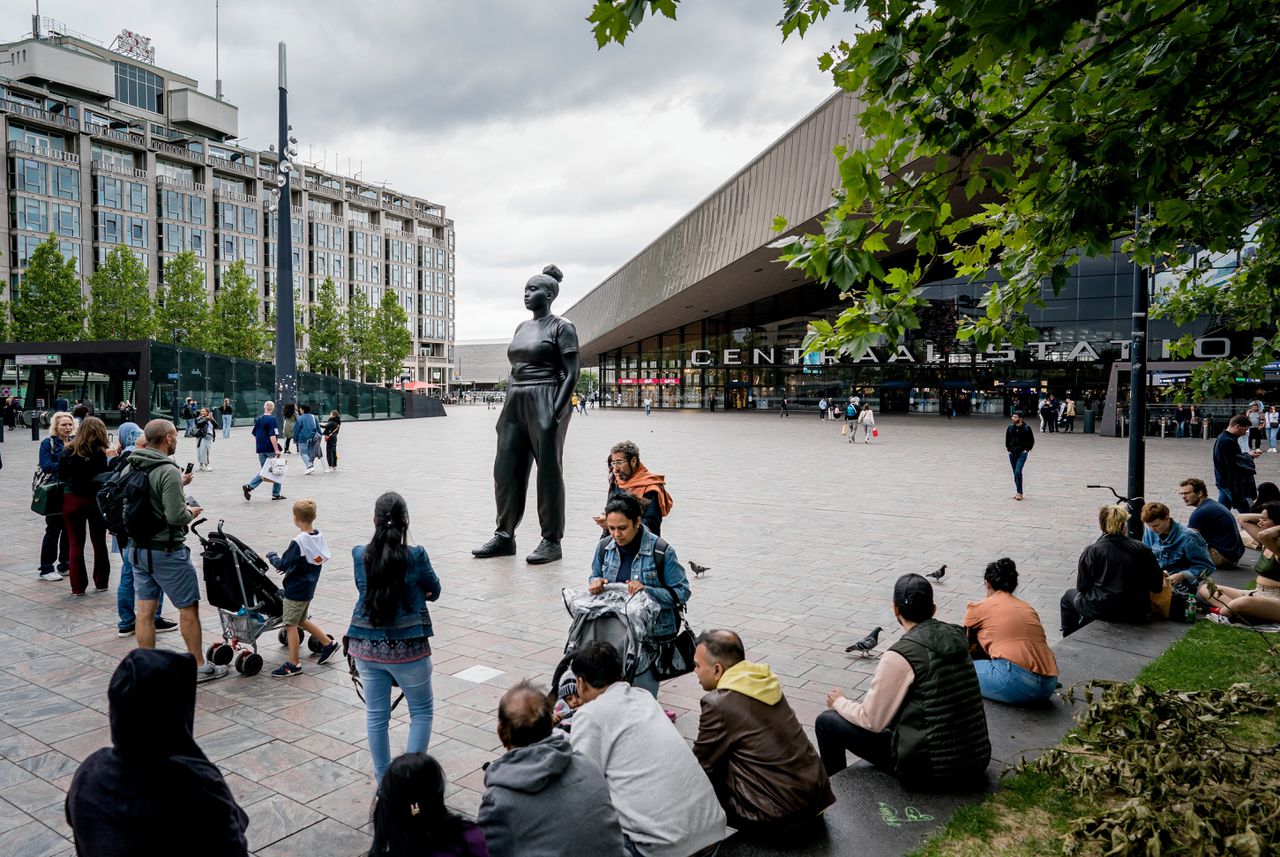 Voorbijgangers maken op het Rotterdamse Stationsplein foto’s van het standbeeld Moments Contained van kunstenaar Thomas J Price.