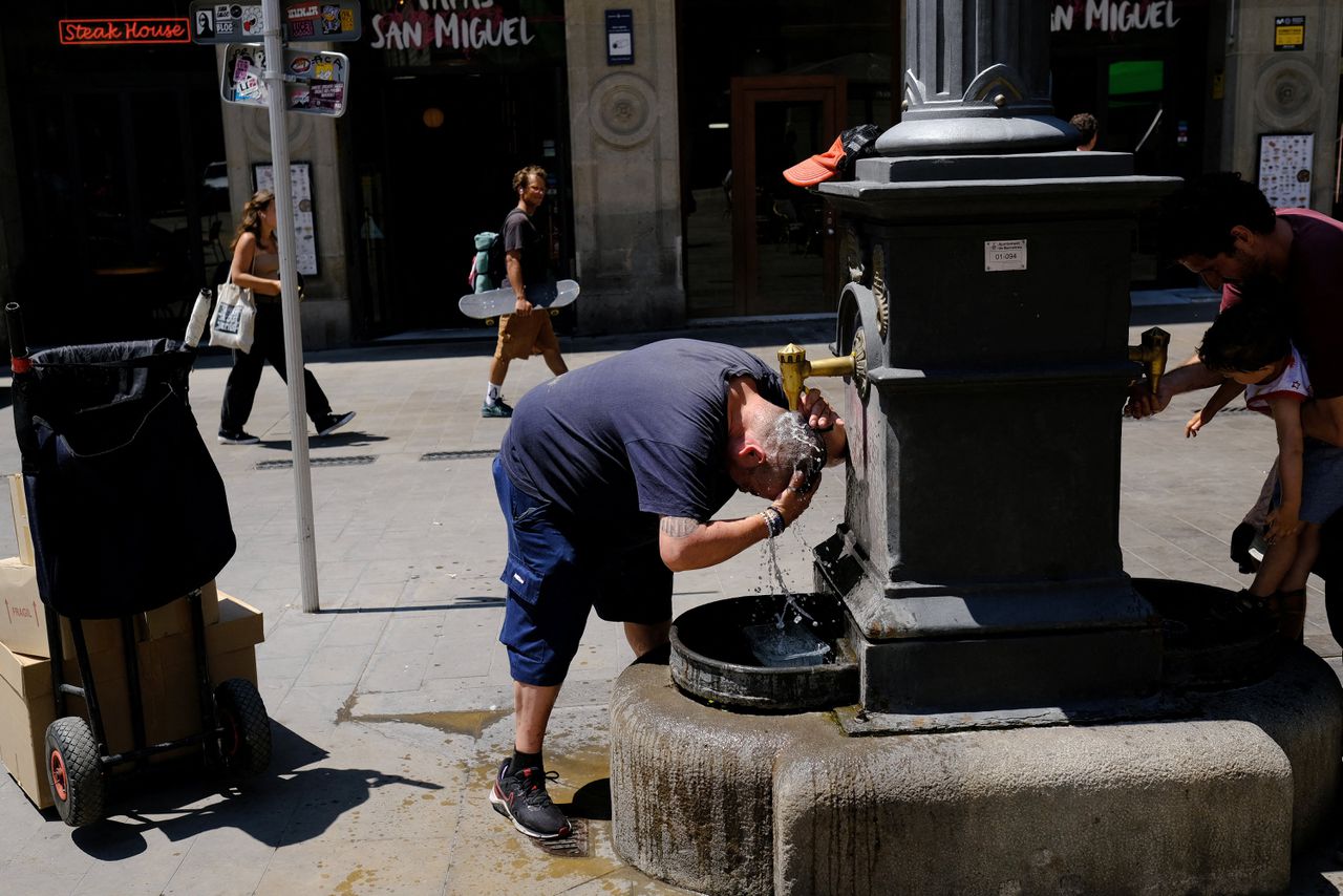 Een pakjesbezorger in Barcelona zoekt verkoeling bij een fontein.