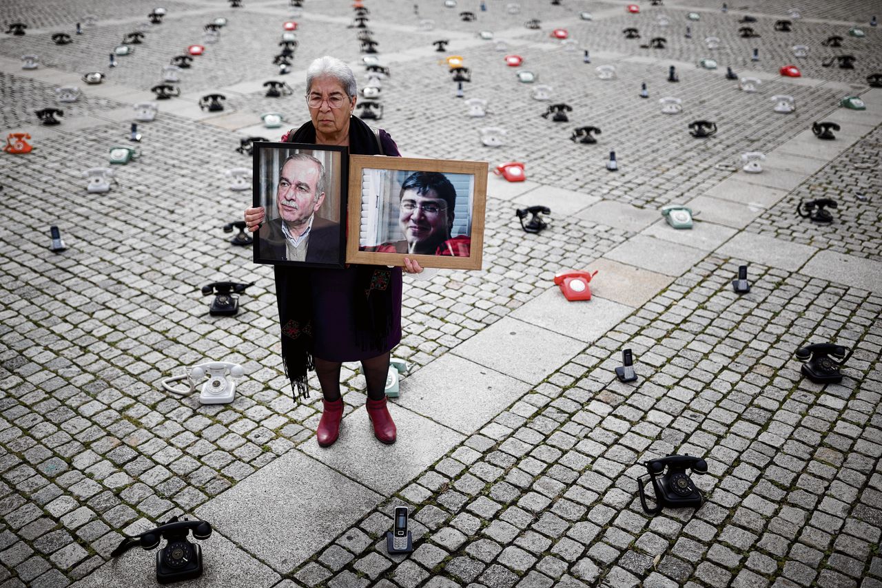 Fadwa Mahmoud, oprichter van een organisatie voor familieleden van vermiste Syriërs, staat met foto’s van haar verdwenen man en zoon in 2021 tussen telefoons op het Bebelplatz in Berlijn.