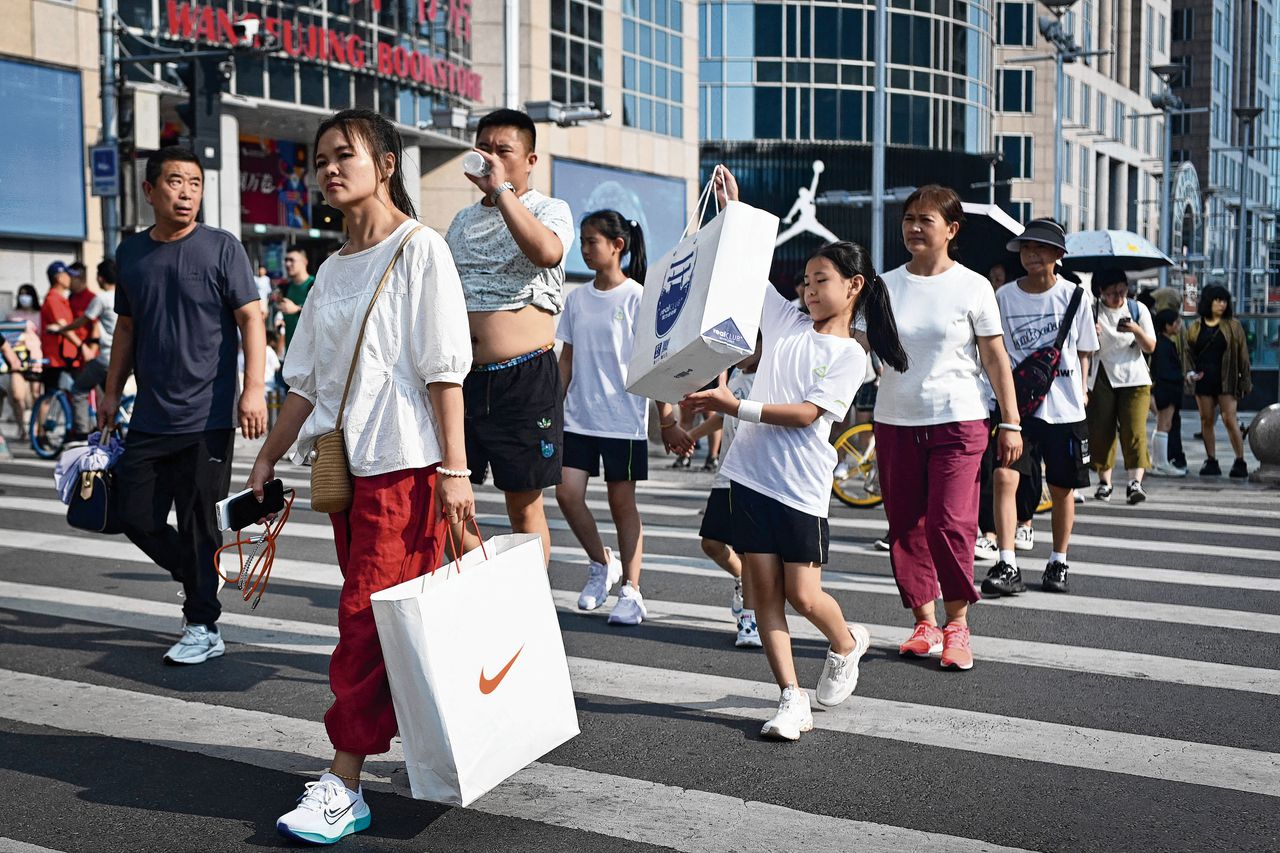 Chinezen winkelen in de hoofdstad Beijing. De groei in winkelverkopen viel vorige maand terug.