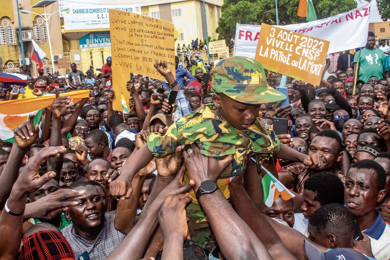 Men hold a child dressed in military uniform as they gather with thousands of anti-sanctions protestors in support of the putschist soldiers in the capital Niamey, Niger August 3, 2023. REUTERS/Mahamadou Hamidou NO RESALES. NO ARCHIVES TPX IMAGES OF THE DAY