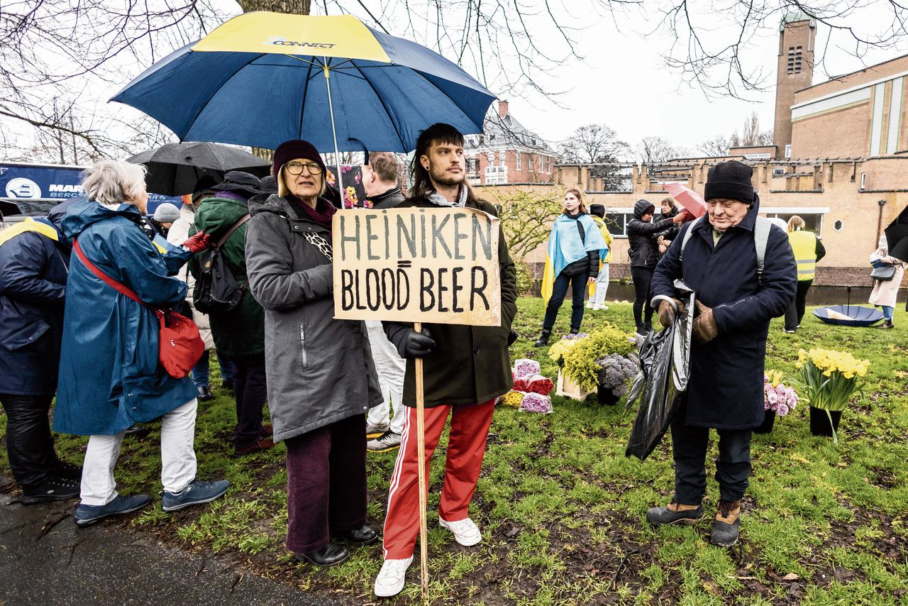 Protestbord tegen ‘Heiniken’ bij een solidariteitstocht voor Oekraïne in Den Haag, een jaar na de Russische inval. Heineken investeert dan nog steeds in Rusland.