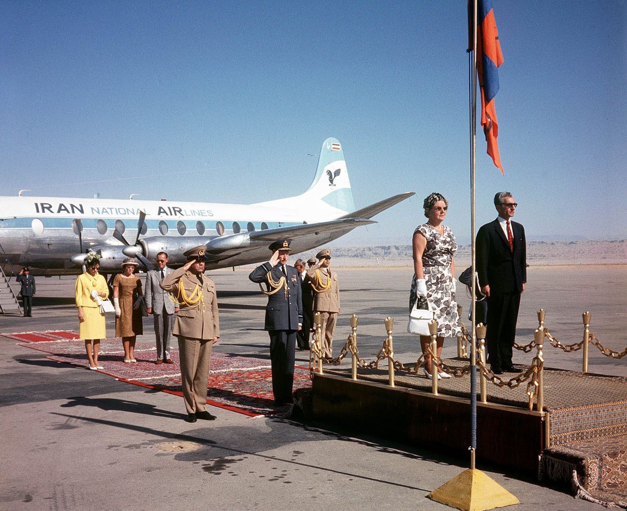 Koningin Juliana en de sjah van Perzië bij aanvang van haar staatsbezoek in 1963, luisterend naar volksliederen in Teheran.