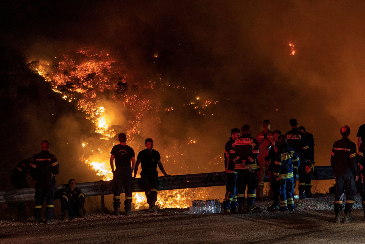 Brandweerlieden kijken naar een bosbrand op de geliefde berg Parnitha in Athene.