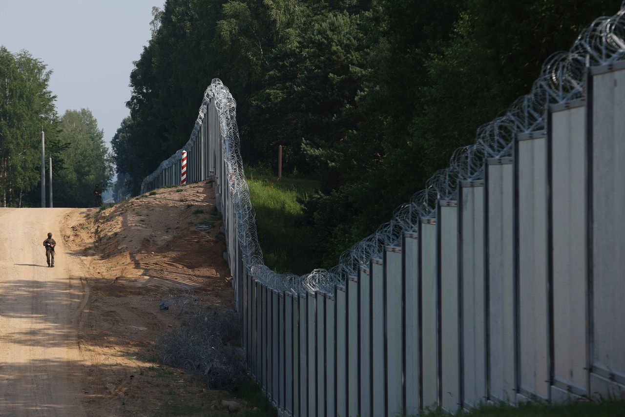 Een Poolse grenswacht patrouilleert langs de metalen muur tussen Polen en Wit-Rusland, in de buurt van Kuznica.