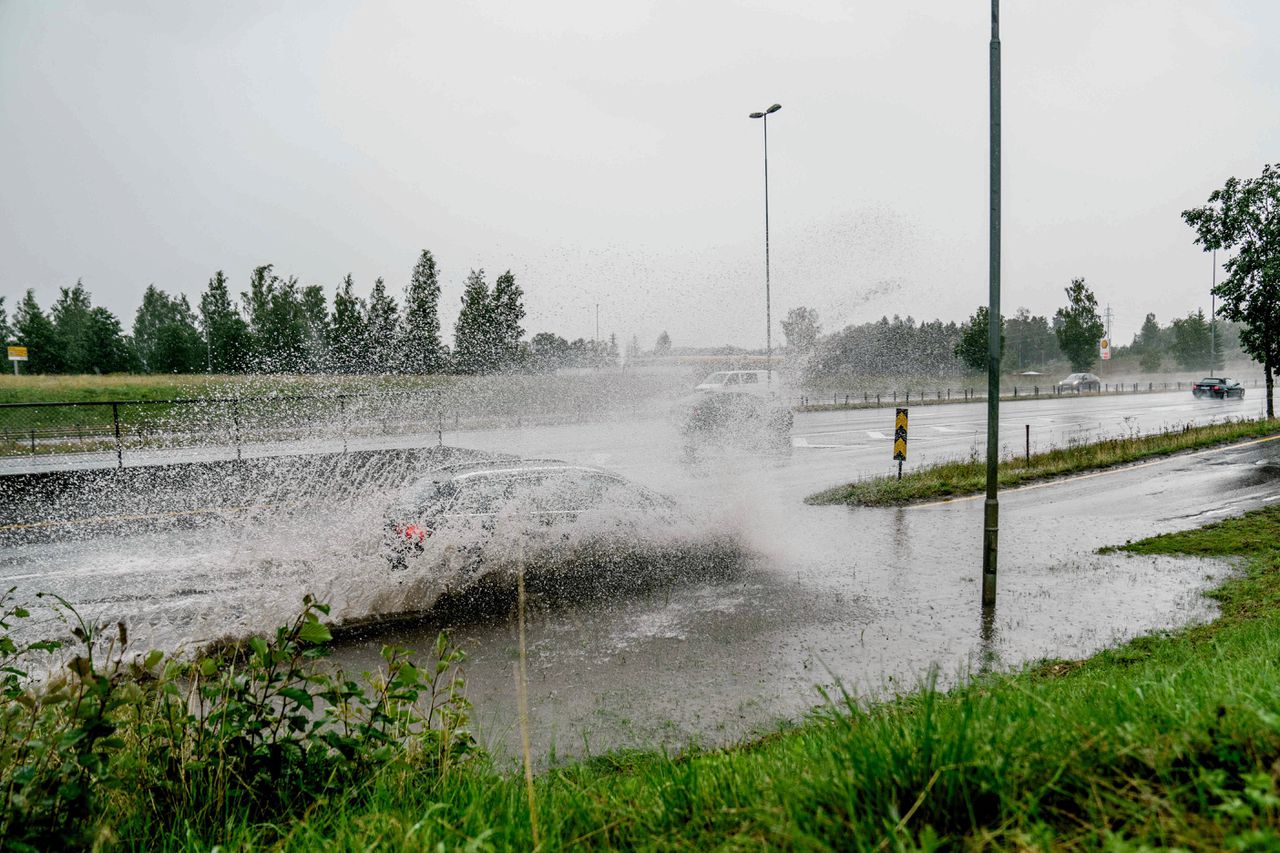 In Noorwegen rijdt een auto door een diepe plas.