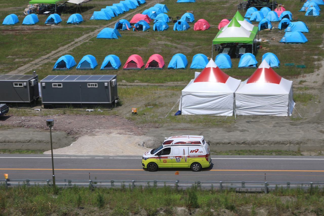 Een ambulance rijdt voorbij een camping van de World Scout Jamboree.