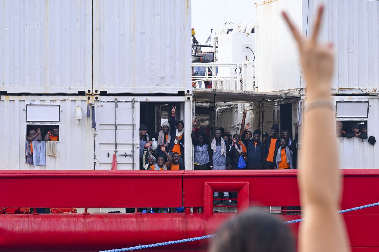 Een persoon gebaart naar migranten aan boord van het reddingsschip ‘Ocean Viking’ van de ngo SOS Mediterranee bij aankomst in de haven van Napels op 28 augustus.