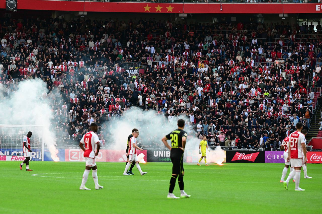 Spelers van Ajax en Feyenoord verlaten het veld nadat er vuurwerk vanaf de tribune is gegooid.