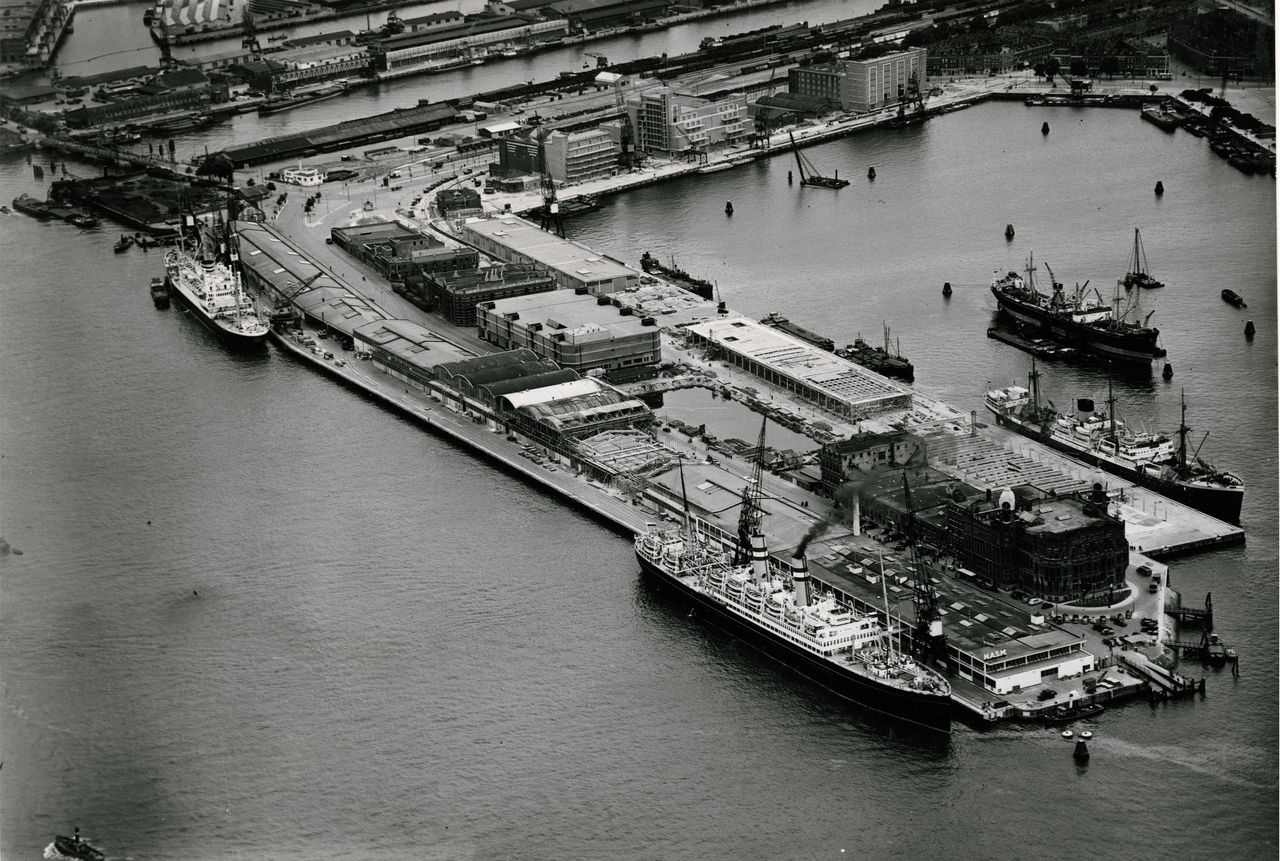 Luchtopname van de terreinen van de Holland-Amerika Lijn en op de voorgrond het kantoorgebouw aan de Wilhelminakade en de Rijnhaven, rechts. Op de achtergrond de Spoorweghaven en links de Nieuwe Maas in 1950