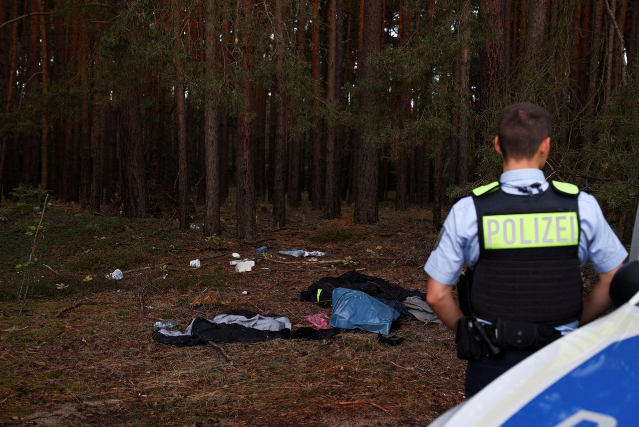 Een Duitse agent in een bos op de grens tussen Polen en Duitsland, waar migranten op doorreis spullen hebben achtergelaten.