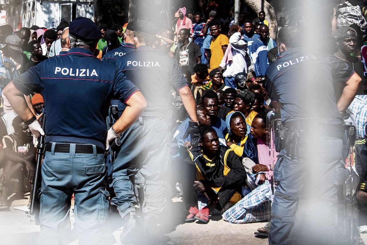 Migranten bij een opvangcentrum of ‘hotspot’, donderdag op Lampedusa.