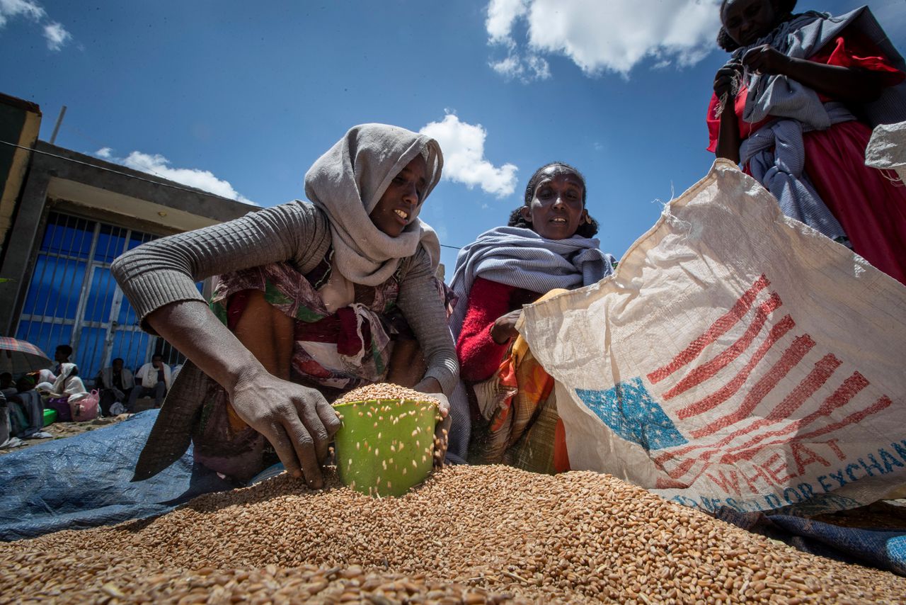 Een vrouw deelt porties tarwe uit aan wachtende gezinnen in de Tigray-regio in het noorden van Ethiopië.