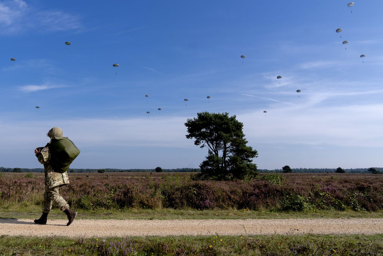 Parachutisten springen uit een vliegtuig tijdens een NAVO-oefening bij Ermelo.