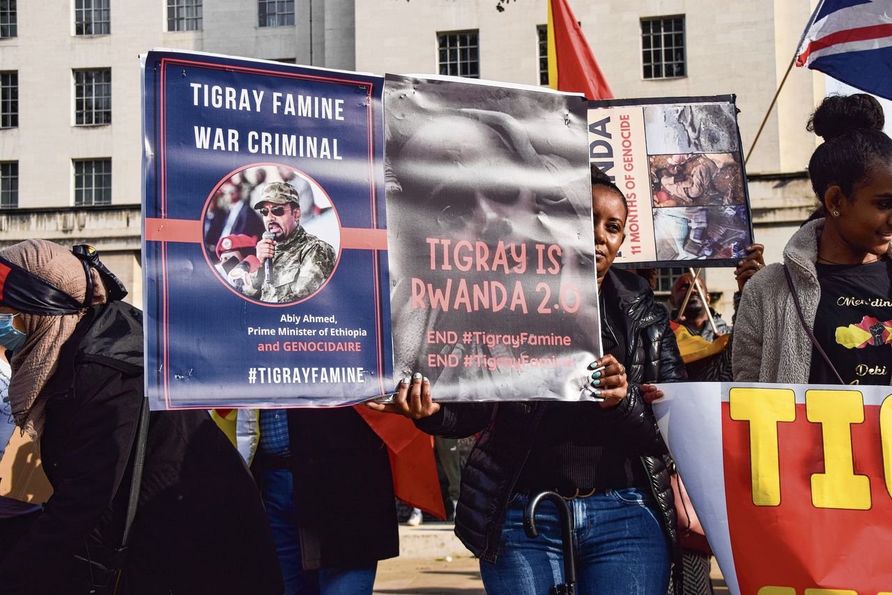 Een betoger in Londen houdt in 2021 affiches omhoog waarop de Ethiopische premier Abiy Ahmed een oorlogsmisdadiger wordt genoemd en de situatie in Tigray wordt vergeleken met de genocide in Rwanda van 1994.