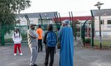 Coumba Moussa, in de felblauwe abaya, brengt haar zoon Souleymane af bij school in Creil. Leerlingen mogen het soepelvallende gewaad niet meer aan op school.