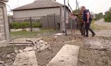 Mensen bij een beschadigd gebouw in de Russische regio Belgorod, op een beeld uit een video na de aanval op het gebied op maandag. 