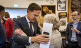 Premier Mark Rutte spreekt een bewoner voordat het kabinet de reactie op het rapport van de parlementaire enquête presenteerde in Garmerwolde.