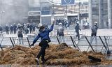 Een demonstrant gooit tijdens het boerenprotest een ei naar de Belgische politie bij de ingang van het Europese parlement in Brussel, afgelopen donderdag.