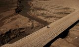 Een man loopt over de door droogte gebarsten grond van een drinkwaterreservoir in het Spaanse Catalonië.