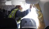 Een medewerker van de toezichthoudende NTSB bekijkt in Portland, Oregon de schade in het toestel van Alaska Airlines.