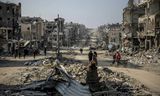 Palestijnen lopen door een straat   in het Noord-Gazaanse Beit Lahia met daarin tientallen volledig verwoeste gebouwen.