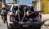 Haïtiaanse  politieagenten  bewaken in januari in Port-au-Prince de begrafenis van drie collega’s  die  door gewapende bendes waren omgebracht.