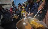 Ontheemde Palestijnen ontvangen voedsel van Arabische en Palestijnse donoren in de stad Deir Al Balah, in het zuiden van de Gazastrook.