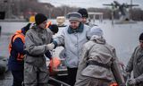 Reddingswerkers helpen een vrouw van boord tijdens een evacuatie in Orsk, Rusland door hoogwater. 