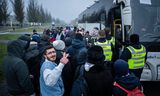 Vluchtelingen bij de bushalte van de pendelbus tussen het asielzoekerscentrum in Ter Apel en station Emmen.  