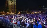 Bezoekers kijken op een groot scherm, op het Oldehoofsterkerkhof in Leeuwarden, naar de optredens van de finale van het Eurovisie Songfestival.