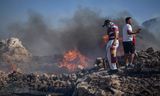 Bewoners blussen een van de natuurbranden bij het zeeresort Lindos, op Rhodos. 