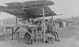 Een verkoopstalletje in november 1945 op  Ambon (Molukken), opgebouwd uit brokstukken puin van  oorlogshandelingen. 